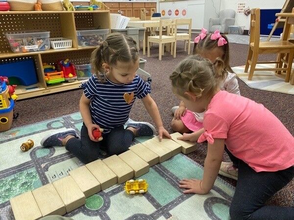 Two children building a wooden block road on a play mat