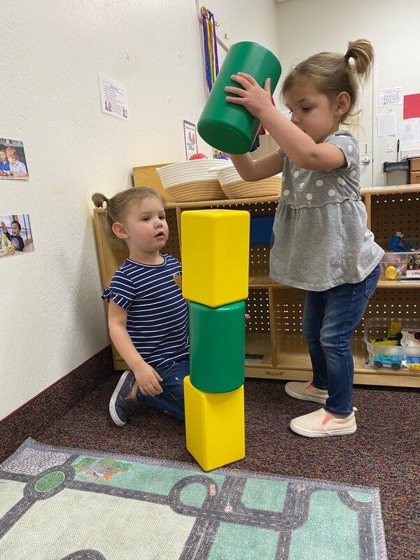 A toddler stacking large foam blocks into a tower