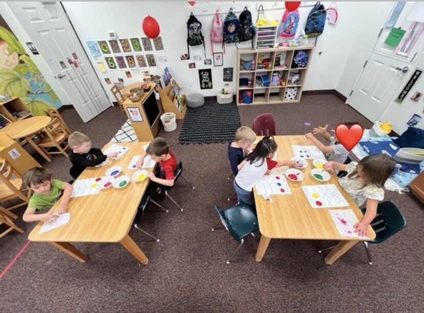 Children and teachers at tables during a classroom activity