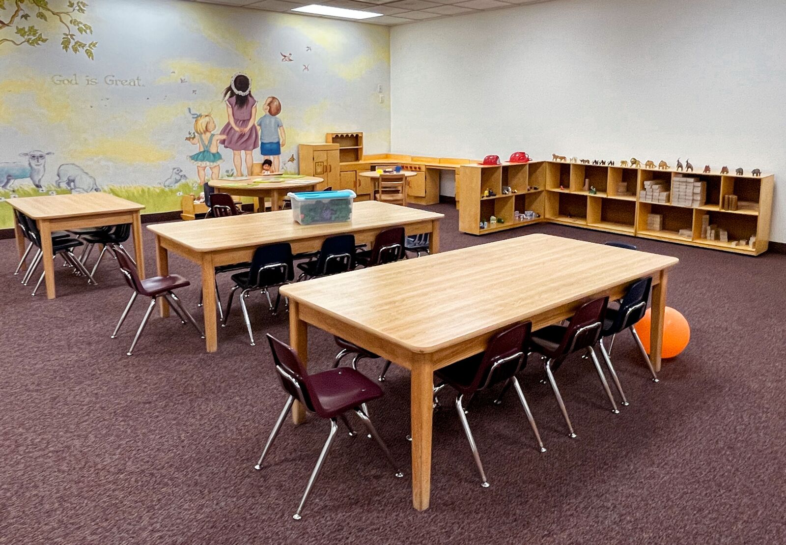 A classroom with tables, chairs, and a painted mural