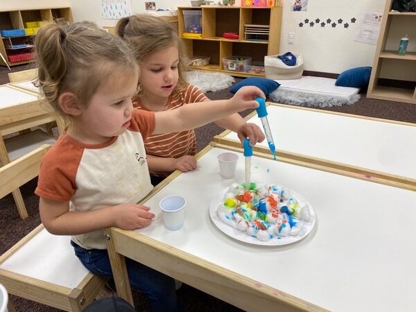 Children using droppers to mix colors at a sensory table