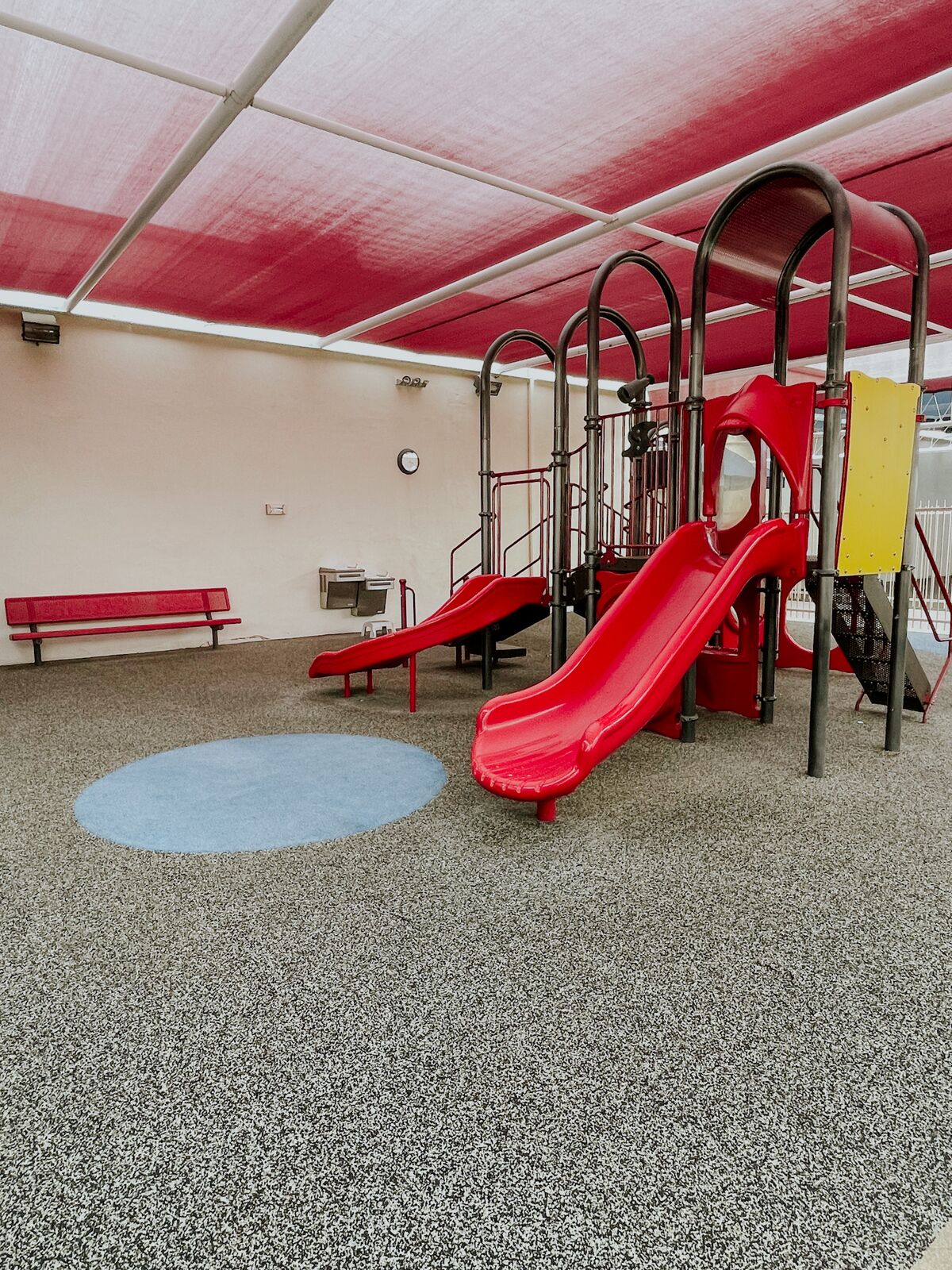 The covered outdoor playground with a slide and climbing structure