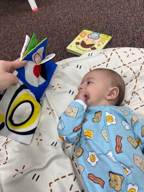 An infant resting and playing with a soft toy