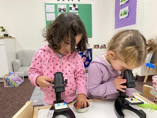 Two children looking through toy microscopes