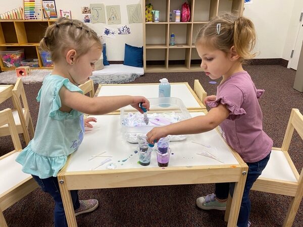 Two children painting at a table