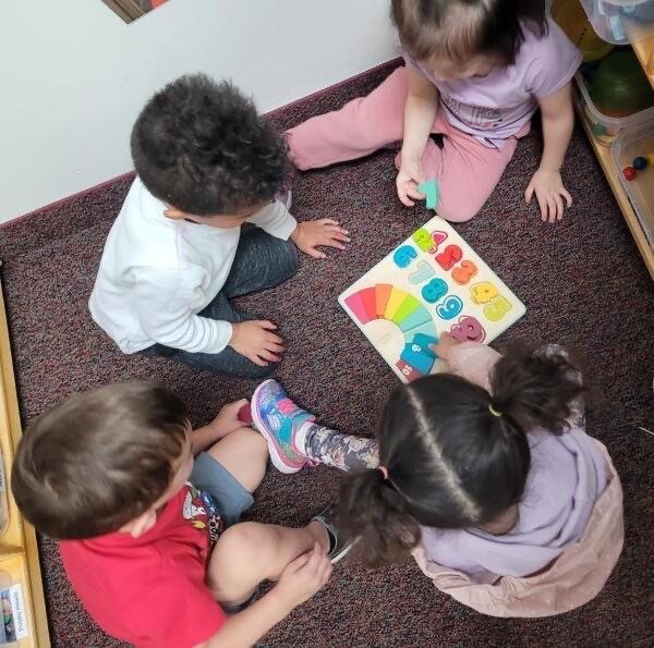 Children working on a puzzle together on the rug