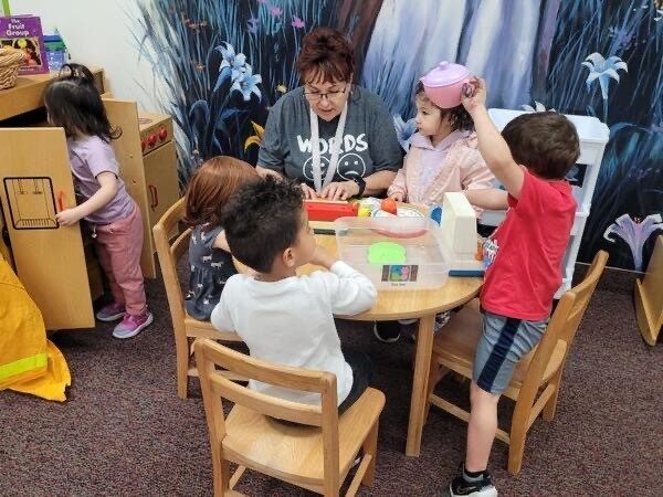 A teacher working with children at a classroom table