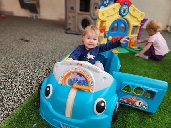 A toddler playing in a ride-on toy car