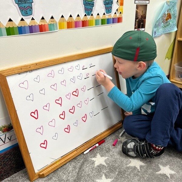 A child tracing hearts on a whiteboard