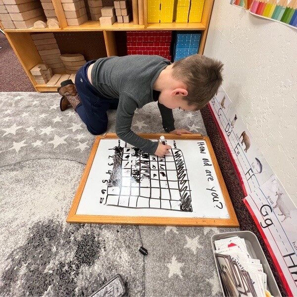 A child drawing on a large whiteboard grid