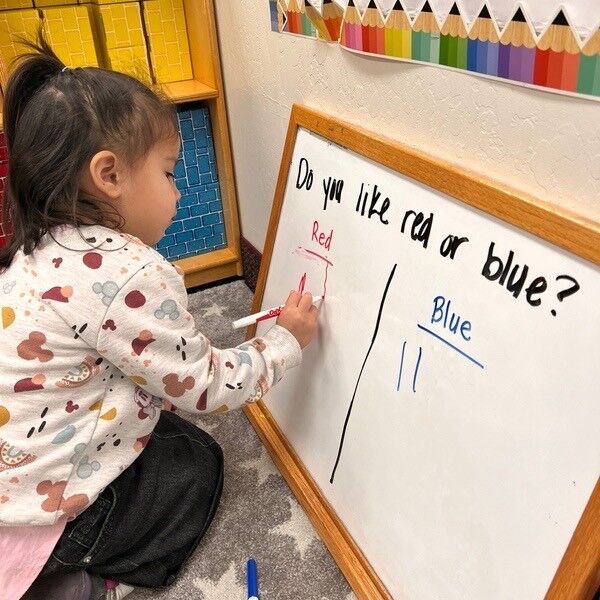 A child writing an answer on a classroom whiteboard