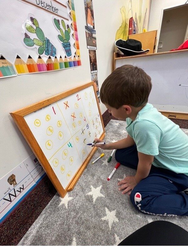 A child writing letters on a whiteboard